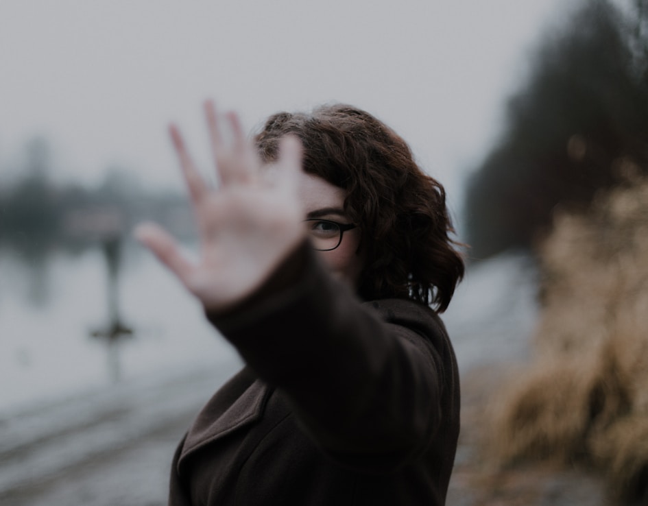 woman in black coat standing near body of water during daytime